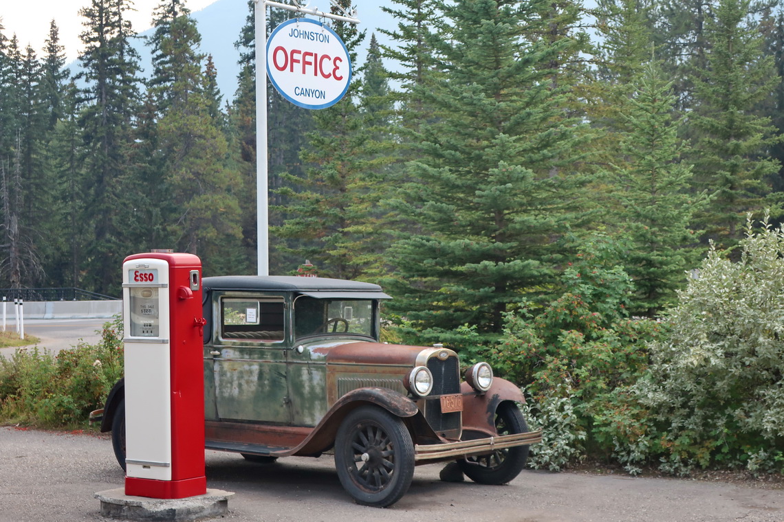 Oldtimer with ancient gas station on the parking lot of Johnston Canyon