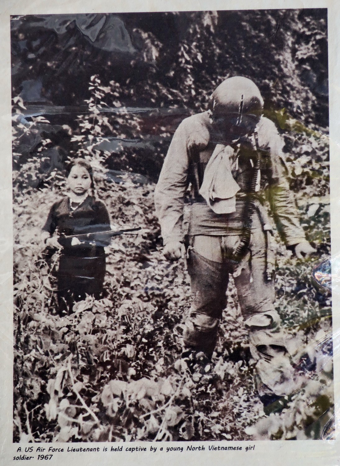 Picture in a shop: A US Aur Force Lieutnant is held captive by a young North Vietnamese Girl Soldier