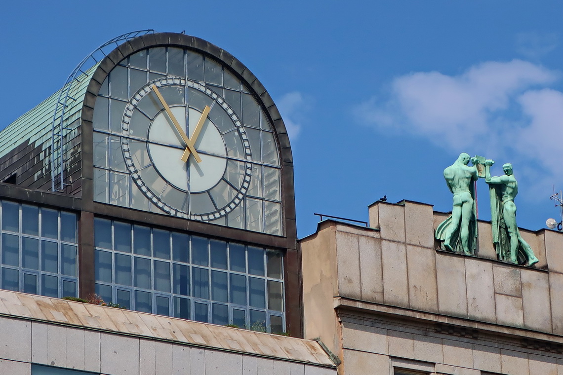 Clock and men on the top of the building opposite of Koruna Palace