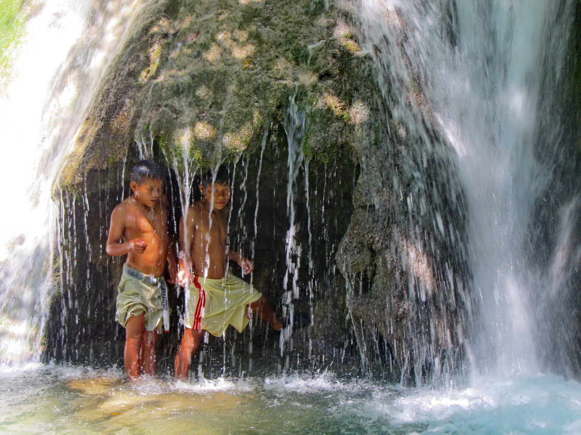 Two boys from Unini with the cave behind the waterfall 	 	